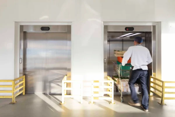 man loading trolley of food pallets into an elevator